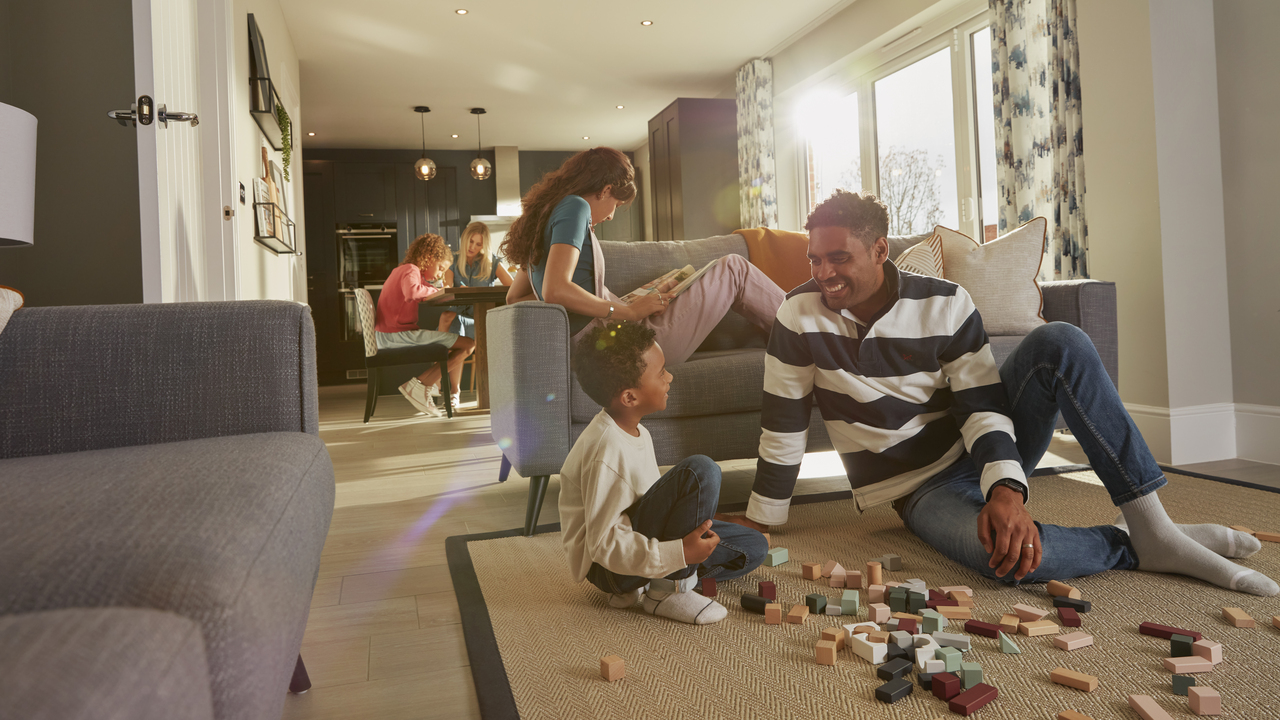 Redrow | inspiration | A couple sit with their 2 children on a sofa