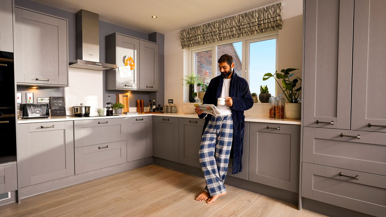 Redrow - Inspiration - Man reading paper in kitchen enjoying underfloor heating