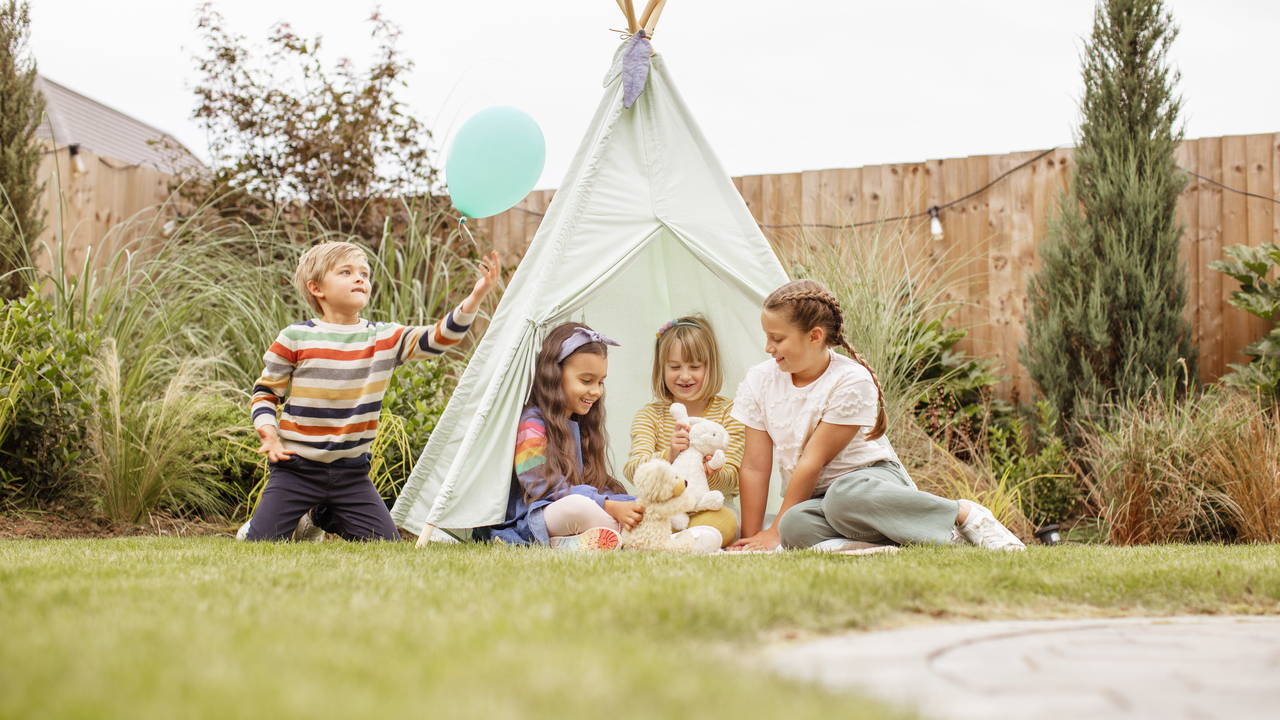 Redrow - Inspiration - Children sat in garden with toys balloon and tent