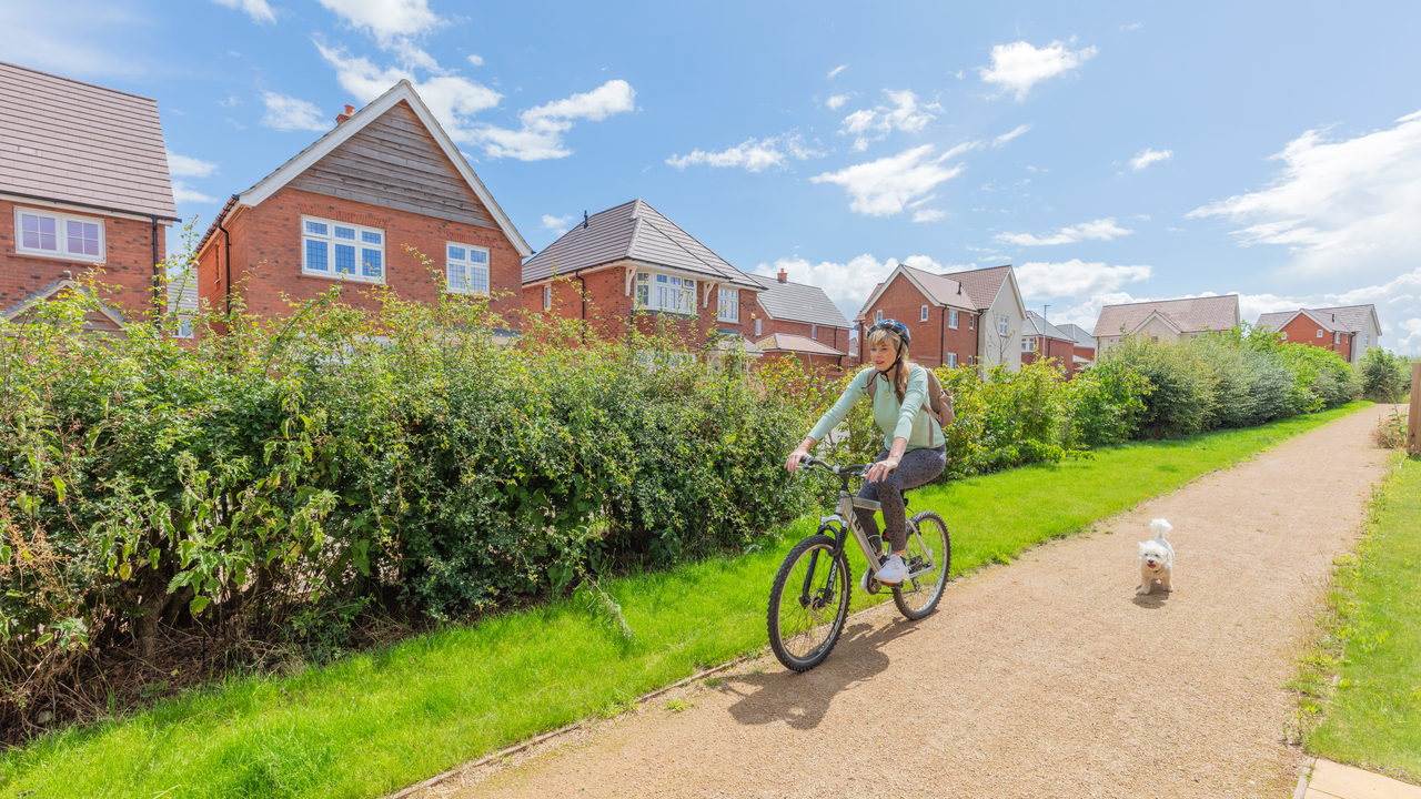 Redrow - Inspiration - Woman cycling next to dog